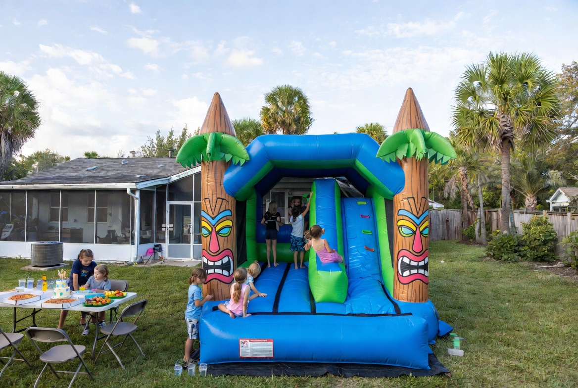 Backyard bounce house combo on grass in a NW Cape Coral yard on a sunny June morning with palm trees