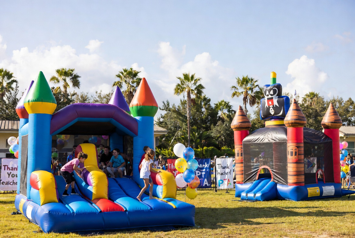 Smiling teacher cutting cake beside a colorful bounce house at a Cape Coral school appreciation party